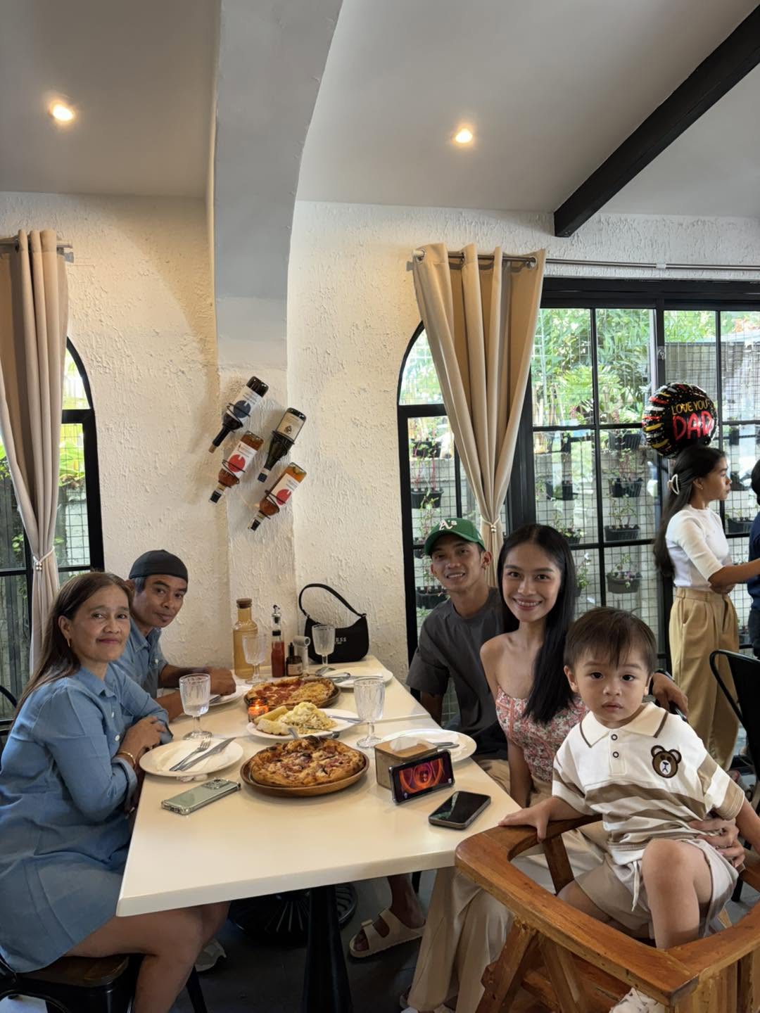 A family gathered around pizza inside Red Tomato Resto Farm